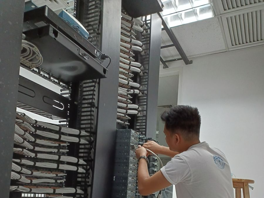 Melquizedek working at a network rack in a server room